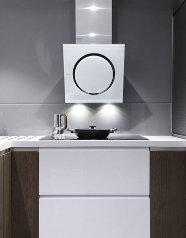 A modern kitchen with a sleek white and stainless steel range hood, a glass backsplash, and a minimalist cooktop. Dark wood cabinetry contrasts with glossy white drawers for a contemporary look.