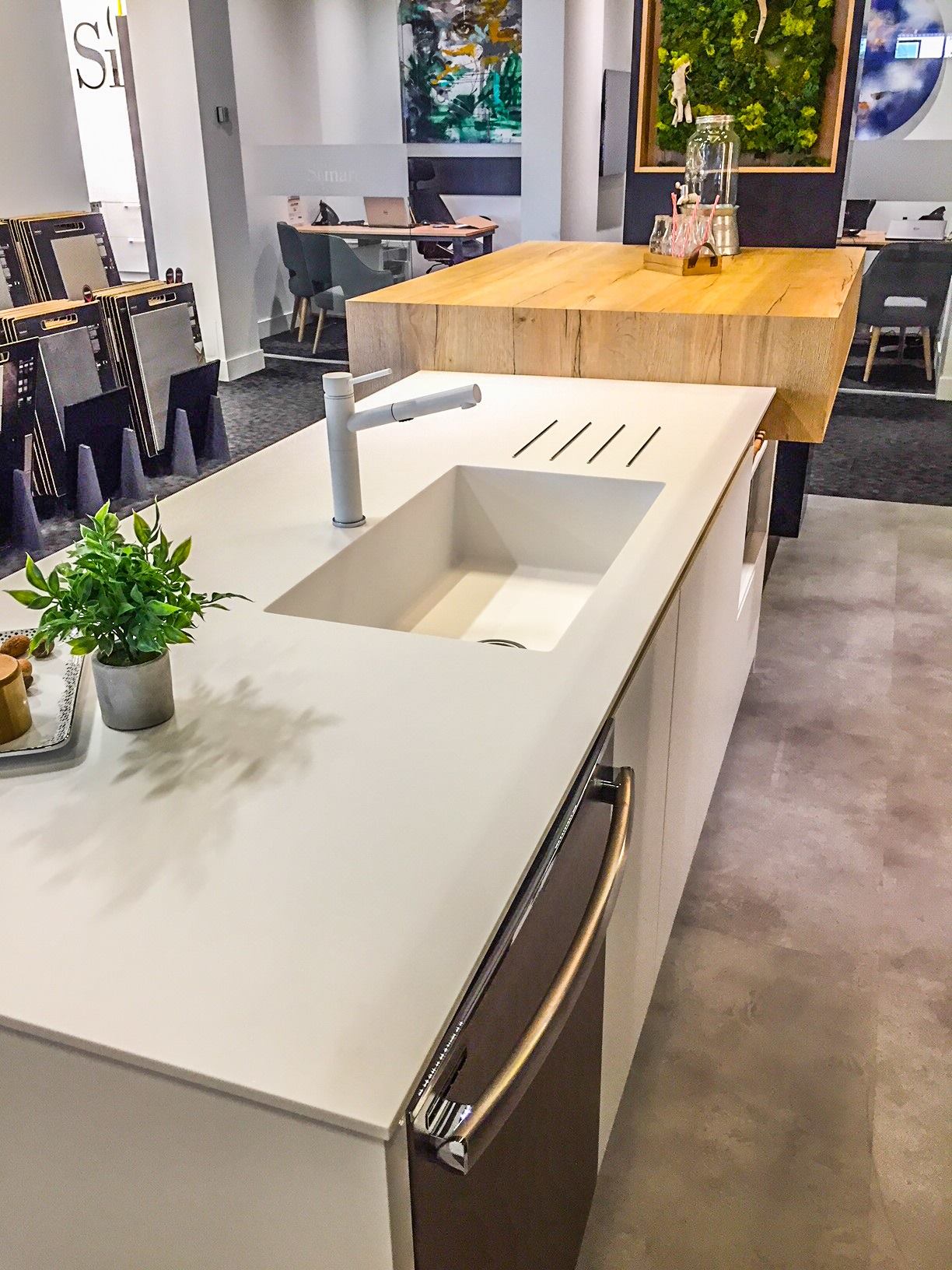 A modern kitchen island featuring a sleek, white countertop with an integrated sink and faucet, complemented by a contrasting wooden countertop extension.
