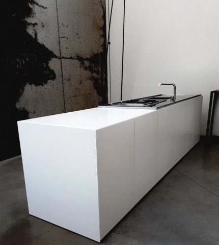 A minimalist kitchen island with a sleek, all-white design. The island features a clean, modern look with sharp lines and a built-in stainless steel faucet and cooktop.