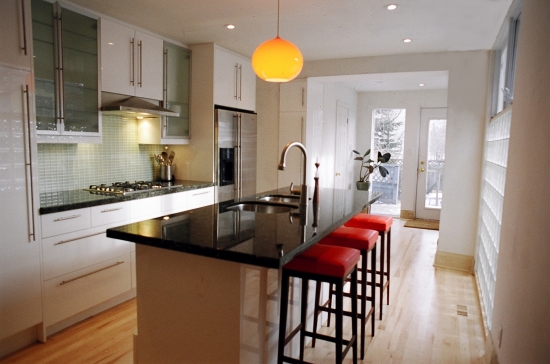 A modern kitchen featuring a sleek black countertop and vibrant red stools for a stylish contrast.