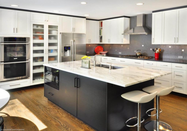 A modern kitchen featuring white cabinets and marble countertops.