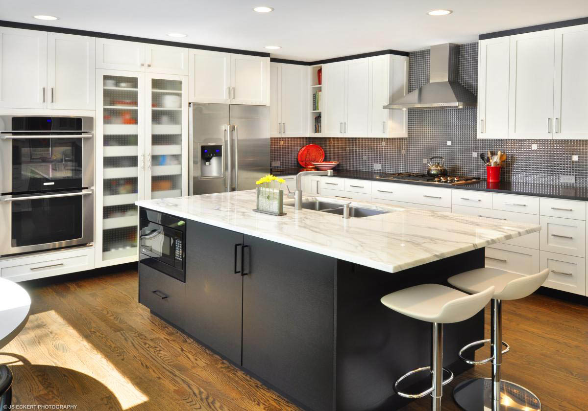 A modern kitchen featuring white cabinets and marble countertops.
