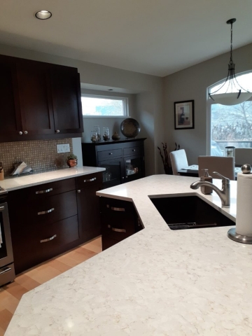 A well-equipped kitchen showcasing a clean sink and a polished countertop, ideal for cooking and meal preparation.