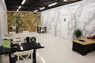 A spacious room features a marble wall with two tables and several chairs.