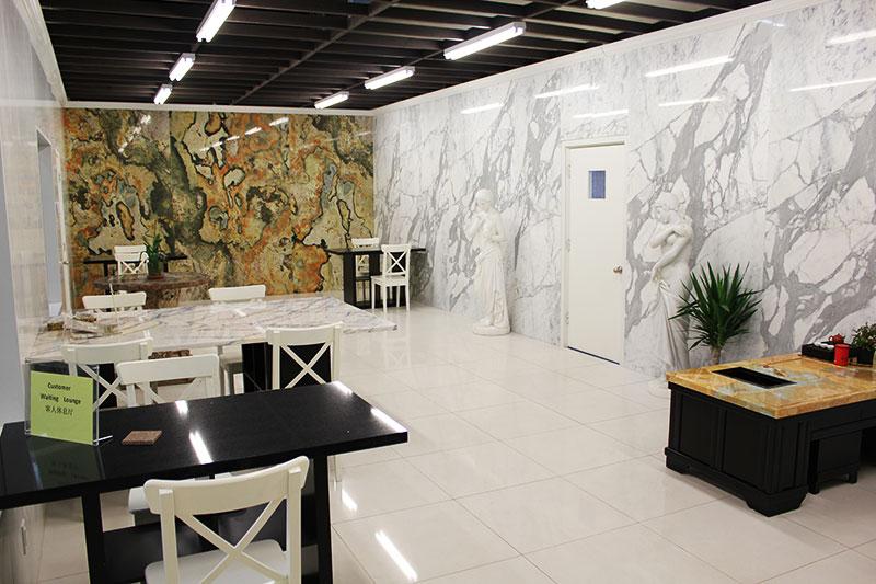 A spacious room features a marble wall with two tables and several chairs.