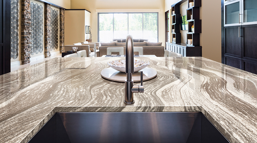A marble veined countertop with a deep sink with brown open shelving in the background and a large window.